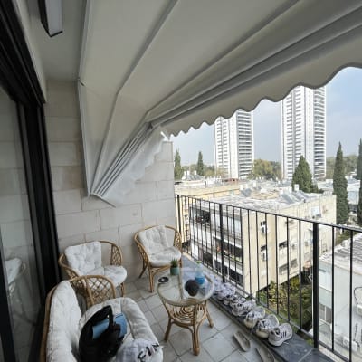 מרפסת עם סוכך לבן פתוח מעל רהיטים