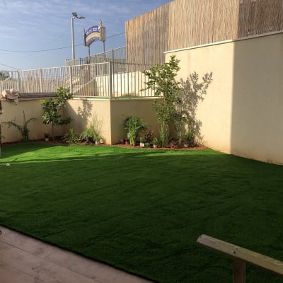 גינה עם דשא סינתטי וצמחים מסודרים בערוגות