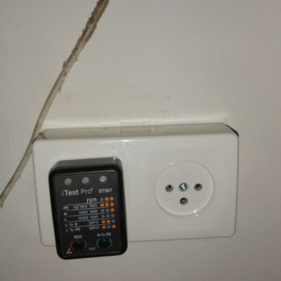 בודק שקע חשמלי ליד שקע בקיר