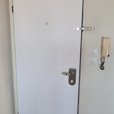 דלת לבנה עם ידית מתכת ובריח בטיחות