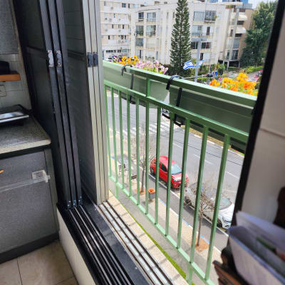 מסגרת חלון פתוחה עם נוף למרפסת וגדר ירוקה