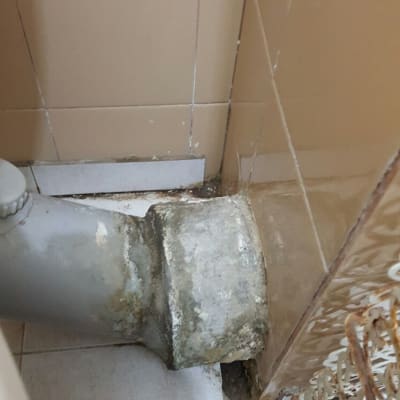 צינור ביוב אפור עם סימני רטיבות על הקיר
