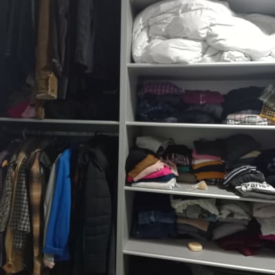 ארון בגדים עם מעילים תלויים ובגדים מקופלים על מדפים