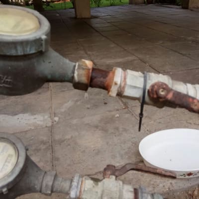 מד מים חלוד עם צינור וברז על רצפה