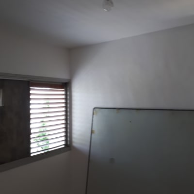 קיר לבן עם נורה חשופה ותאורה טבעית