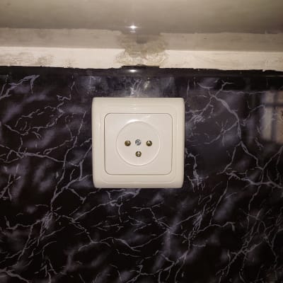 שקע חשמלי מותקן על קיר עם טפט שחור