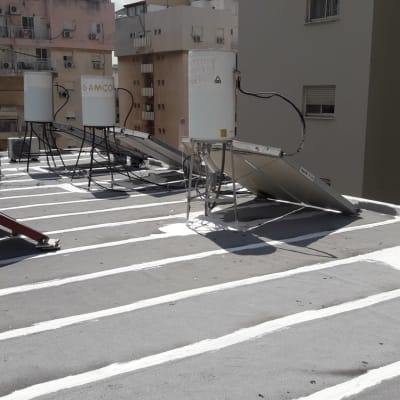 קווים לבנים של איטום על גג שטוח עם דודי שמש