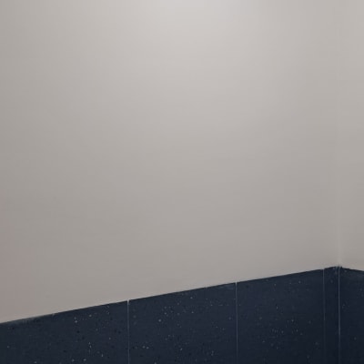 קיר צבוע בלבן מעל אריחים כחולים