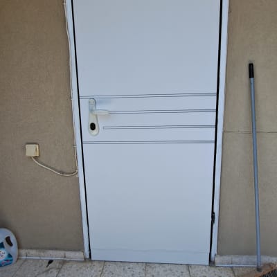 דלת לבנה עם ידית כסופה על רקע קיר חום