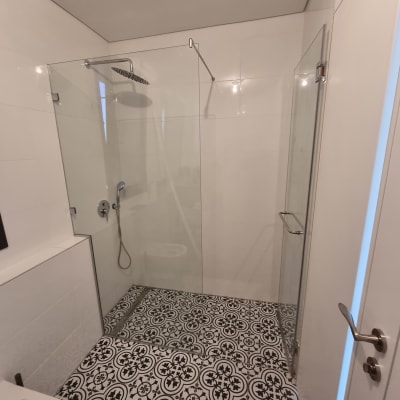 מקלחת עם דלת זכוכית וראש מקלחת מתכתי