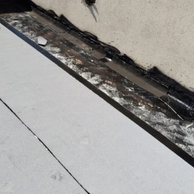 גג עם יריעות איטום אפורות ליד קיר בטון