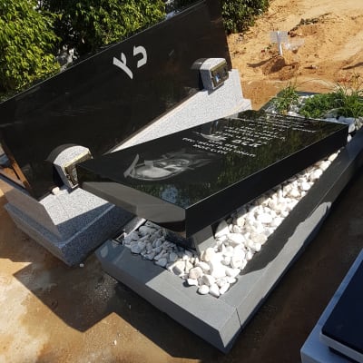 מצבות שחורות עם כיתוב לבן ואבנים לבנות