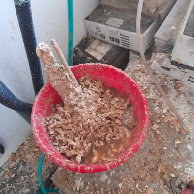 דלי אדום עם חומר חום ומים, צינור ירוק לידו