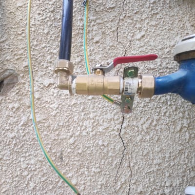 שסתום פליז עם ידית אדומה וצינורות מחוברים