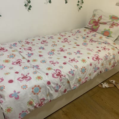 מיטה עם מצעים פרחוניים ונעליים על הרצפה