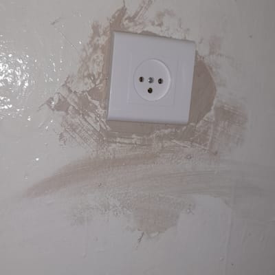 שקע חשמל בקיר עם סימני תיקון סביבו