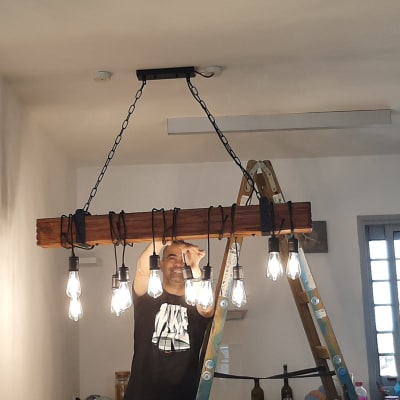 חשמלאי מתקין נברשת עם נורות על סולם