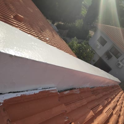 איטום גג עם חומר לבן על רעפים אדומים