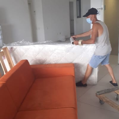 אדם מזיז מזרן עטוף בניילון בחדר ריק