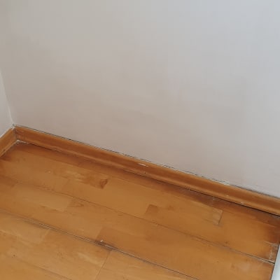 קיר צבוע בלבן עם פאנל עץ בתחתית