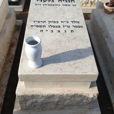 מצבות עם כיתוב בעברית ואגרטל לבן על אחת מהן