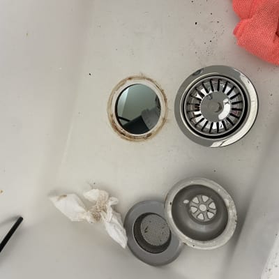 כיור עם מסננת נירוסטה, פתח ניקוז ומטלית אדומה