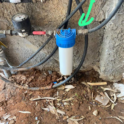 מסנן מים כחול מחובר לצינורות מתכת על קיר