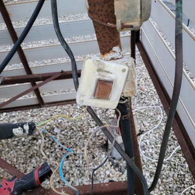 חוטי חשמל חשופים ומקדחה אדומה על הקרקע