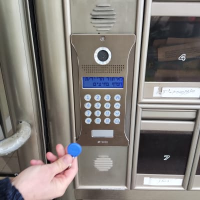 אינטרקום עם מקלדת ומסך תצוגה, יד מחזיקה תג כחול