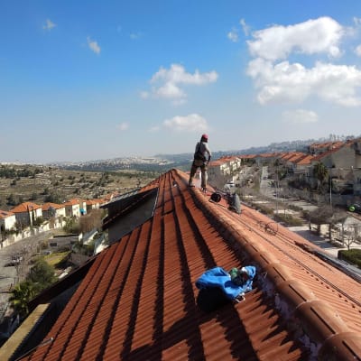 אדם עובד על גג רעפים עם ציוד בטיחות