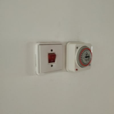 שקע חשמלי עם מתג אדום וטיימר על קיר לבן