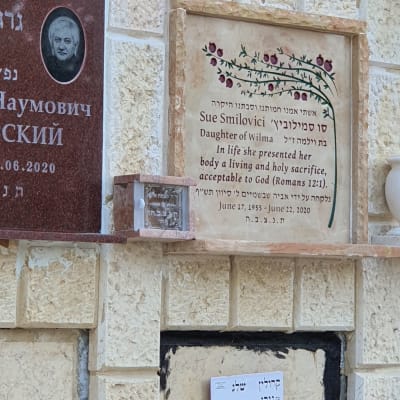 מצבות עם כיתוב בעברית ואנגלית על קיר אבן