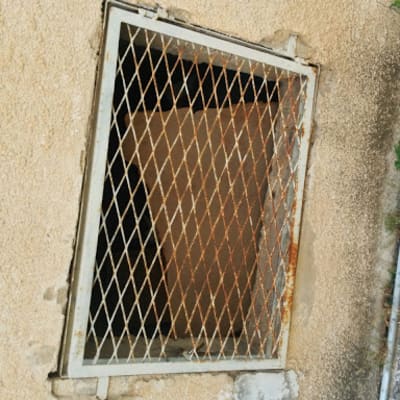 מסגרת מתכת עם רשת חלודה על קיר בטון