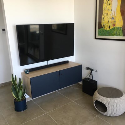 טלוויזיה תלויה על הקיר מעל ארונית עץ