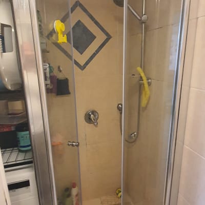 מקלחון עם דלתות זכוכית, ראש מקלחת ומדף מוצרים