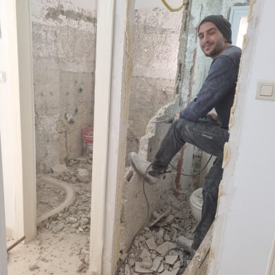 אדם עובד על שיפוץ קיר עם מקדחה