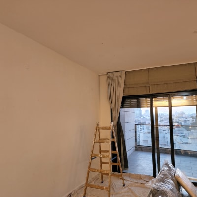 סולם עץ ליד קיר צבוע חלקית