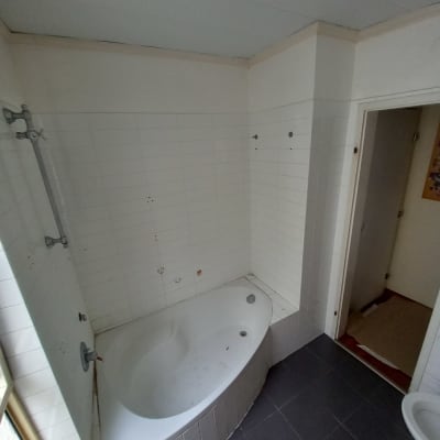 חדר אמבטיה עם אריחים לבנים ואמבטיה פינתית