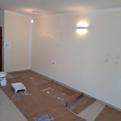 חדר עם קירות צבועים, דלי צבע ומגש על הרצפה