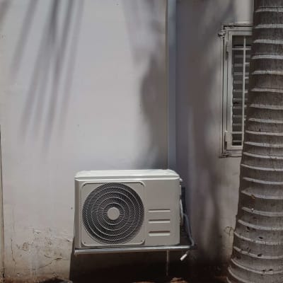 יחידת מיזוג אוויר חיצונית מותקנת על קיר לבן