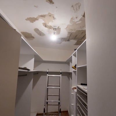 סולם מתכת מתחת לתקרה מתקלפת עם נורה חשופה