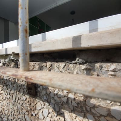 סדק בקיר אבן מתחת לחלון עם מסגרת מתכת חלודה