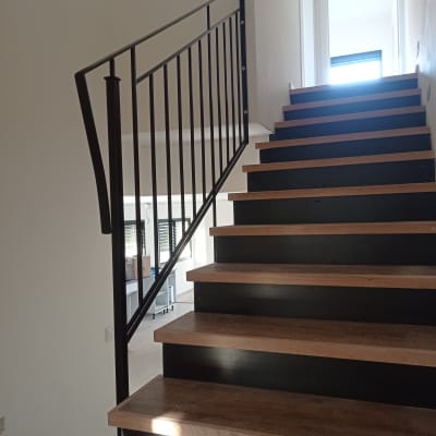 מעקה מתכת שחור על מדרגות עץ בבית