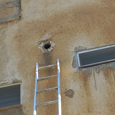 סולם ליד חור בקיר חיצוני של בניין