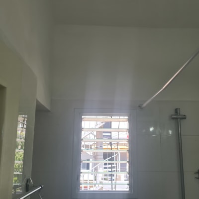 קיר צבוע בלבן עם חלון ומוט תלייה