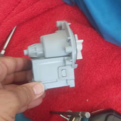 יד מחזיקה רכיב פלסטיק אפור על רקע אדום