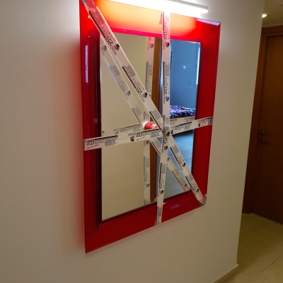 מראה עם מסגרת אדומה וסרטי הדבקה על הזכוכית