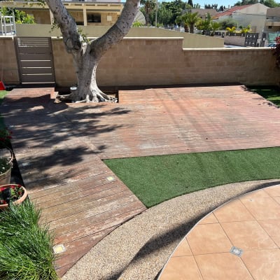 דק עץ עם עץ גדול ודשא סינתטי בגינה