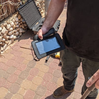 אדם מחזיק מכשיר אלקטרוני ליד ציוד בדיקה