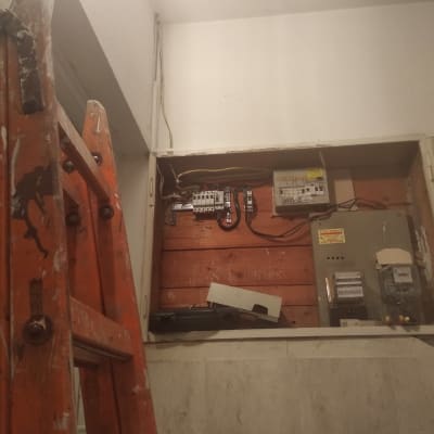 ארון חשמל פתוח עם חוטים וסולם כתום